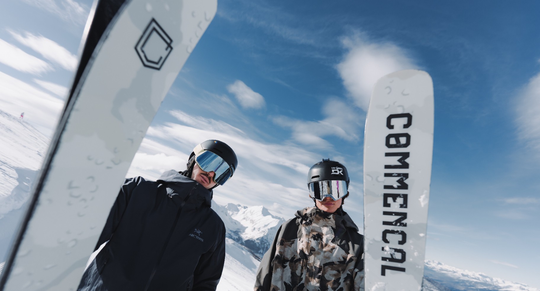 2 skiers smiling on a lift chair, snow and snowy trees in the background